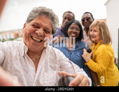 Buon uomo anziano che si diverte con gli amici in sottofondo Foto Stock