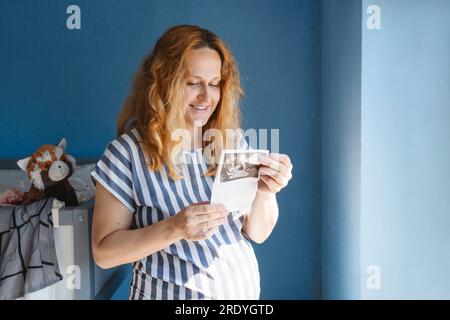 Donna felice incinta che guarda le immagini ecografiche Foto Stock