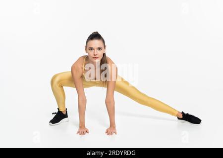 vesti la donna sportiva in abiti attivi, allenandosi su sfondo bianco, concetto di attività fisica Foto Stock