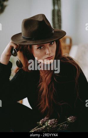 Donna rossa con cappello e occhiali da sole Foto Stock