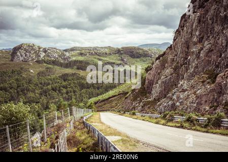 tranquilla piccola strada di campagna che si snoda tra le montagne della scozia Foto Stock