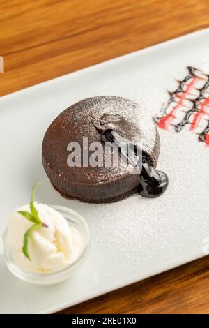 Souffle al cioccolato con cioccolato scorrevole su un piatto di porcellana bianca Foto Stock