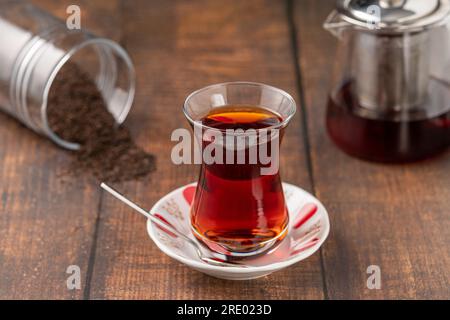 Tè turco appena preparato in una tazza di vetro a vita sottile su un tavolo di legno Foto Stock