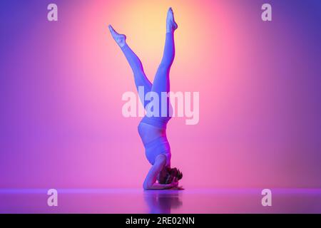 Donna incinta che fa esercizio sul poggiatesta al neon Foto Stock