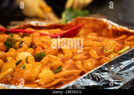 Deliziosa cucina coreana Tteokbokki, gustosa torta di riso speziata con salsicce, uova al mercato per spuntini di Street food. Foto Stock