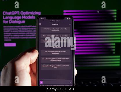 Azzorre, Portogallo - 21.01.2023: Pagina Web ChatGPT con lo smartphone che tiene la mano e sullo sfondo sfocato il logo della parola ChatGPT sullo schermo di un laptop. Foto Stock