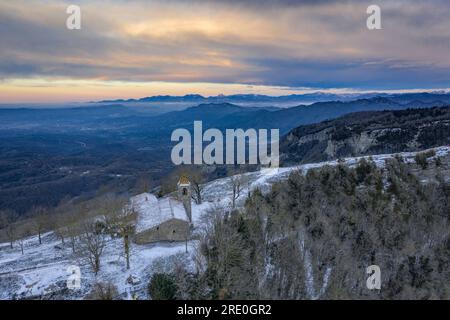 Vista aerea delle scogliere e del santuario di Cabrera all'alba invernale con neve a Collsacabra (Osona, Barcellona, Catalogna, Spagna) Foto Stock