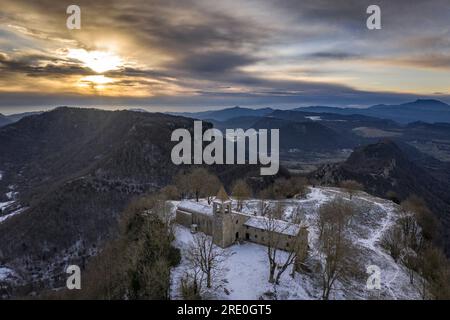 Vista aerea delle scogliere e del santuario di Cabrera all'alba invernale con neve a Collsacabra (Osona, Barcellona, Catalogna, Spagna) Foto Stock