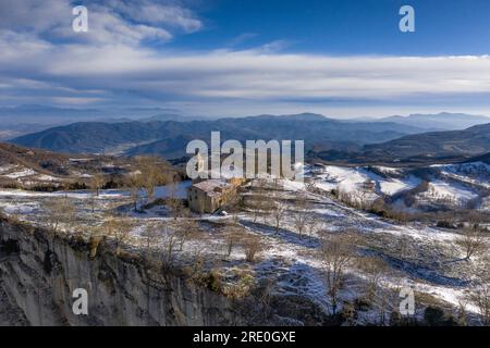 Vista aerea delle scogliere e del santuario di Cabrera all'alba invernale con neve a Collsacabra (Osona, Barcellona, Catalogna, Spagna) Foto Stock