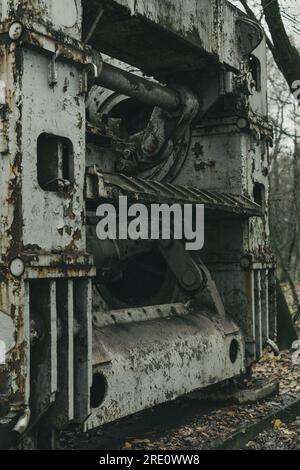 Una vecchia macchina defunta per la lavorazione delle lamiere nella foresta. Produzione di ferro e acciaio. Macchina per la storia industriale. Macchinari abbandonati e arrugginiti. Foto Stock