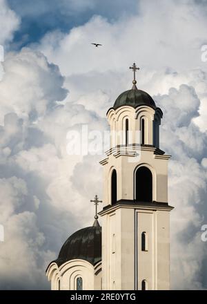 Campanile della chiesa ortodossa e piccione che volano accanto ad essa contro una grande nuvola bianca, simbolo di Dio e della fede Foto Stock