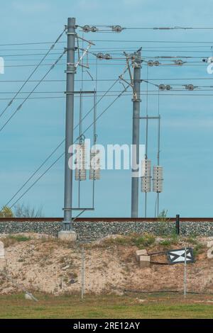 Linea ferroviaria elettrica polo di tensione con fili e pesi in calcestruzzo, messa a fuoco selettiva Foto Stock