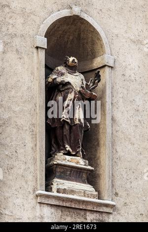 Statua usurata e danneggiata sulla facciata della chiesa cattolica, particolare dell'architettura cristiana Foto Stock