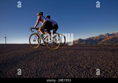 Due ciclisti che scalano il leggendario col (passo del Granon) in autunno, nelle Alpi francesi. Un paio di ciclisti su una strada di montagna. Foto Stock