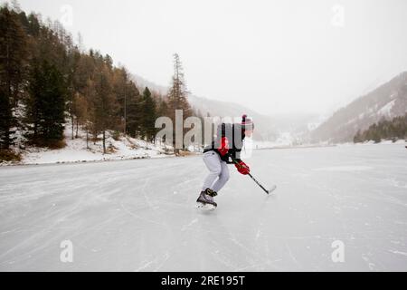 Villar Saint Pancrace (Francia sud-orientale): Pattinaggio su ghiaccio in inverno su un lago ghiacciato. Gente che gioca a hockey sul ghiaccio sul lago Orceyrette. Giovane m Foto Stock