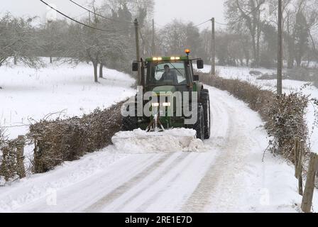 Contadino che pulisce la neve da una strada di campagna. Contadino che pulisce le strade di accesso a un villaggio Foto Stock