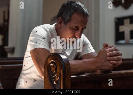uomo che prega in chiesa Foto Stock