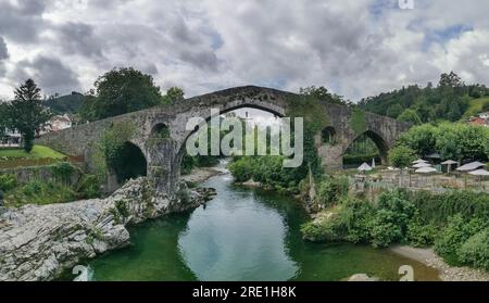 León Spagna - 07 05 2021: Vista panoramica sul ponte romano sul fiume Sella, un ponte iconico sulla città di Cangas de Onís, Picos de Europa o Peak Foto Stock