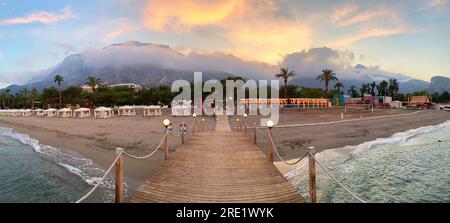 Vista sulla spiaggia della Riviera turca con le montagne del Tauro sullo sfondo. Al tramonto. Foto Stock