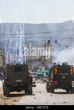 Nalus, Palestina. 24 luglio 2023. Veicoli militari israeliani corazzati che sparano bombole di gas lacrimogeni ai palestinesi durante un'operazione militare all'interno del campo, a est di Nablus, nella Cisgiordania occupata. L'esercito israeliano fece irruzione nei campi di Nour Shams, ad est di Tulkarm, e Aqabat Jabr a Gerico, Askar, ad est di Nablus, durante un'operazione congiunta allo stesso tempo per arrestare persone ricercate. (Foto di Nasser Ishtayeh/SOPA Images/Sipa USA) credito: SIPA USA/Alamy Live News Foto Stock