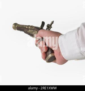 Mano con una pistola vintage. Imitazione di una vecchia pistola del XVIII secolo nelle mani di un uomo su sfondo bianco Foto Stock