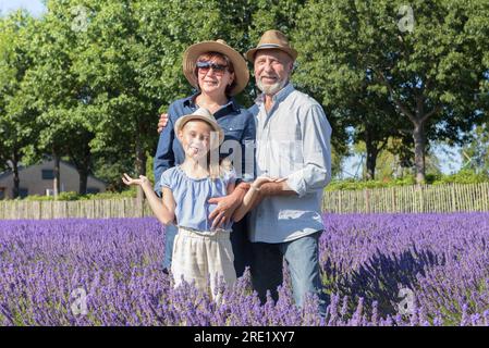 Felice ritratto estivo in famiglia in un campo di lavanda in fiore. Uomo, donna e ragazza in piedi su fresche piante aromatiche nelle giornate di sole. Foto Stock