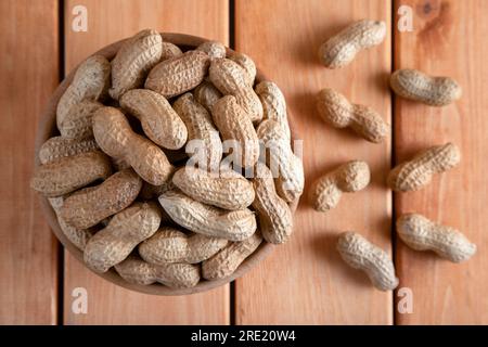 Recipiente pieno di arachidi sgusciate su un tavolo di legno Foto Stock