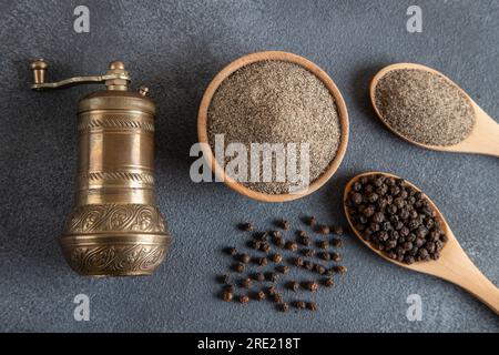 Grani di pepe nero, pepe nero macinato e mulino per metalli, vista dall'alto Foto Stock