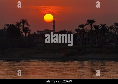 Sole che si trova dietro il minareto sul Nilo Foto Stock