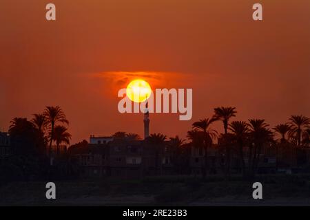 Sole che si trova dietro il minareto sul Nilo Foto Stock