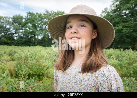 Mietitura. Ragazza adolescente con un cappello a setole larghe sul campo. Ritratto al lavoro Foto Stock