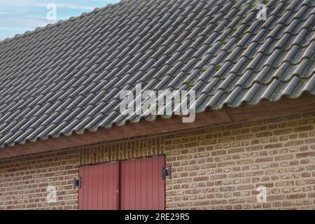 Il tetto di un vecchio edificio piastrellato. Frammento di mattoni e persiane per finestre degli anni passati Foto Stock