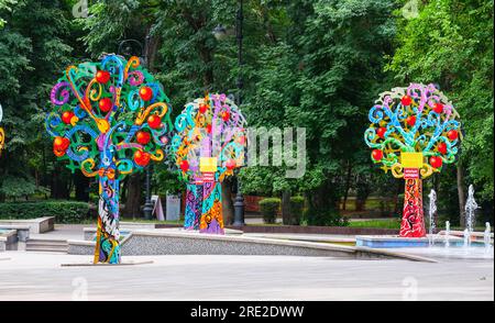 Kazakistan, Almaty. Alberi decorativi colorati vicino alla fontana, Central Park for Culture and Recreation. Foto Stock