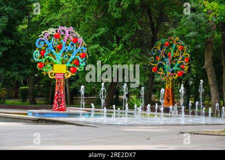 Kazakistan, Almaty. Alberi decorativi colorati vicino alla fontana, Central Park for Culture and Recreation. Foto Stock