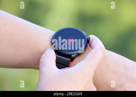 Smart Watch su mano femminile che misura il livello di ossigeno nel sangue. Display rotondo con app per il monitoraggio dello stato Foto Stock