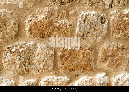 Primo piano della vecchia texture di sfondo della parete in pietra beige. Superficie del castello, antica pietra naturale Foto Stock