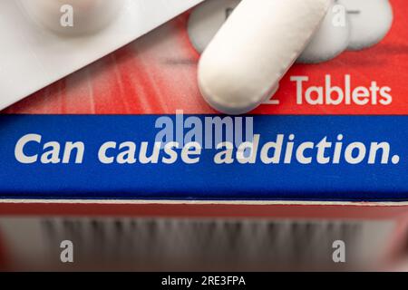 Un concetto di dipendenza medica con una scatola di medicinali contenenti oppioidi e l'avvertimento che può causare dipendenza. Foto Stock