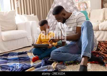 Padre e figlio afroamericani felici che usano il tablet a casa Foto Stock