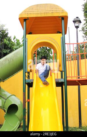 Un latinoamericano di 9 anni dalla pelle scura gioca a giochi all'aperto durante le sue vacanze in povertà Foto Stock