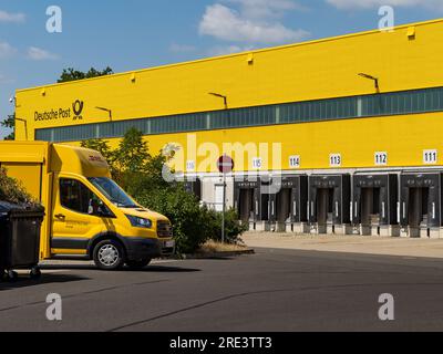 Centro di distribuzione DHL (MechZB) con un veicolo di consegna davanti. Le zone di carico sono vuote. L'edificio giallo dell'industria proviene dalla Deutsche Post Foto Stock