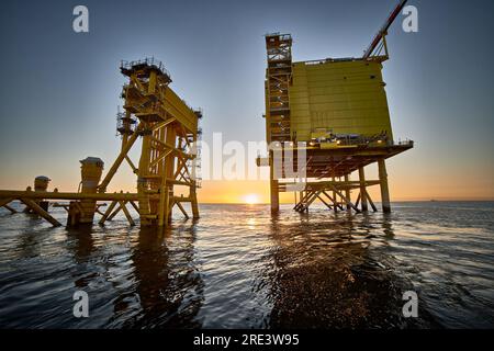 Vista della stazione di distribuzione elettrica offshore per parchi eolici al tramonto in mare. Foto Stock