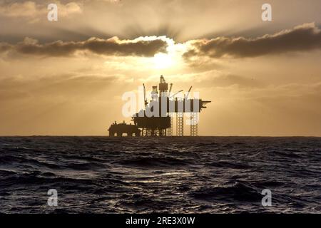 ISilhouette di un carro di perforazione con martinetto nel Mare del Nord al tramonto. Piattaforma offshore del mare del Nord per petrolio e gas. Foto Stock