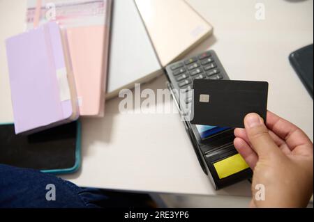 Primo piano con carta di credito bianca nera su un terminale POS, per effettuare pagamenti online senza contanti tramite tecnologia NFC. Internet mobile banking. Foto Stock