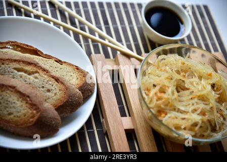 Spaghetti di riso coreani con carne e spezie. Tagliatelle con salsa e pane. Noodle Stick. Foto Stock