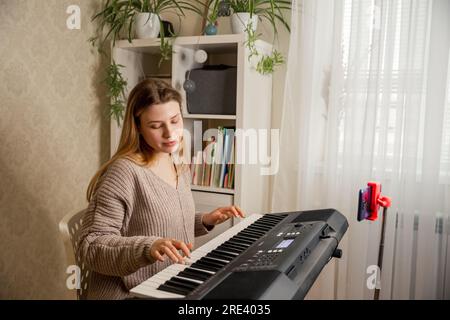 Giovane insegnante di musica che suona pianoforte elettrico insegnando a distanza Foto Stock