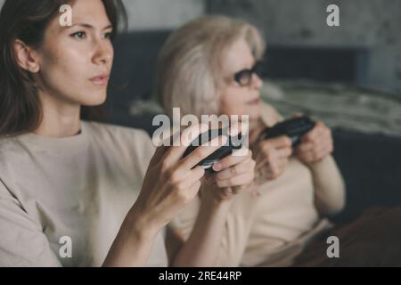 Due donne che giocano ai videogame per console con controller joystick, emotiva, gesto, reazione. Famiglia felice. Intrattenimento per computer. Foto Stock