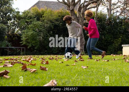 Felici madre e figlio afroamericani che giocano a football in giardino Foto Stock