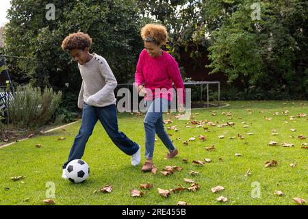 Felici madre e figlio afroamericani che giocano a football in giardino Foto Stock