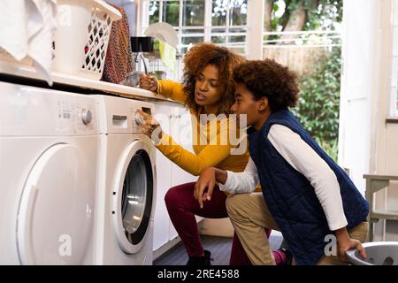 Felici madre e figlio afro-americani che fanno il bucato Foto Stock