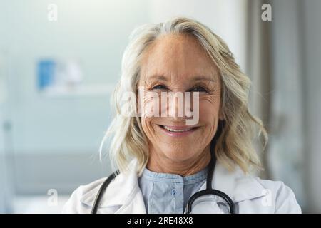 Ritratto di medico femminile caucasico anziano felice che indossa camice da laboratorio e stetoscopio in ospedale Foto Stock